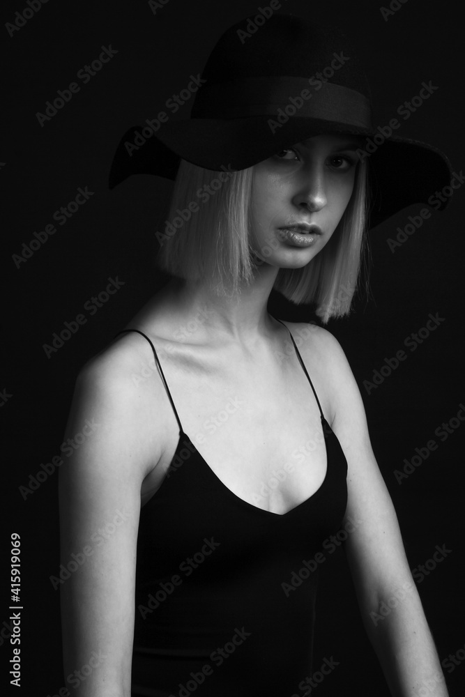 Black and white portrait blondes on a black background in a hat and Tank Top With Thin Straps. Black and white portrait blondes on a black background in a hat and Tank Top With Thin Straps.