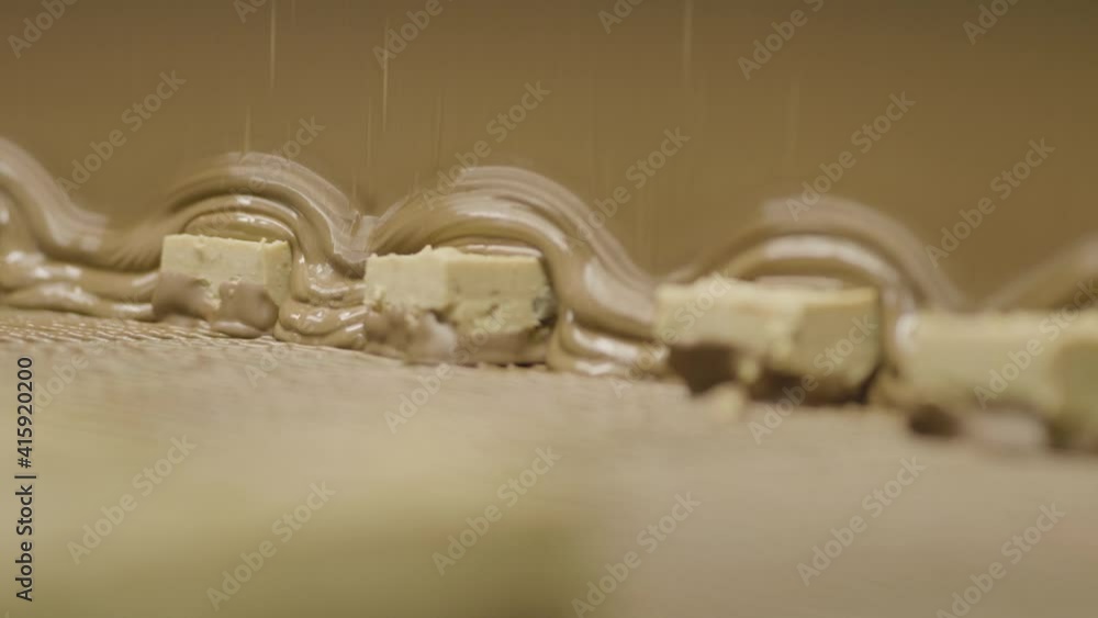 4K Shallow Focus Low Angle White Chocolate Bars Running Through Chocolate Coating on Conveyor Belt 4K Shallow Focus Low Angle White Chocolate Bars Running Through Chocolate Coating on Conveyor Belt