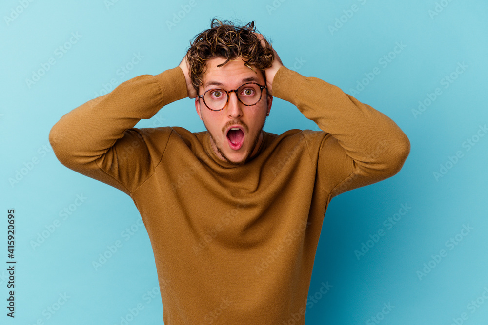 Young caucasian man wearing eyeglasses isolated on blue background screaming, very excited, passionate, satisfied with something. Young caucasian man wearing eyeglasses isolated on blue background screaming, very excited, passionate, satisfied with something.
