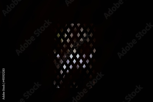 view of a confessional grille in the darkness of a church