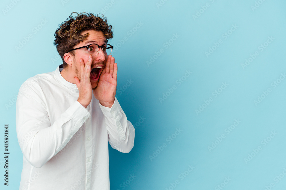 Young caucasian business man isolated on blue background shouts loud, keeps eyes opened and hands tense. Young caucasian business man isolated on blue background shouts loud, keeps eyes opened and hands tense.