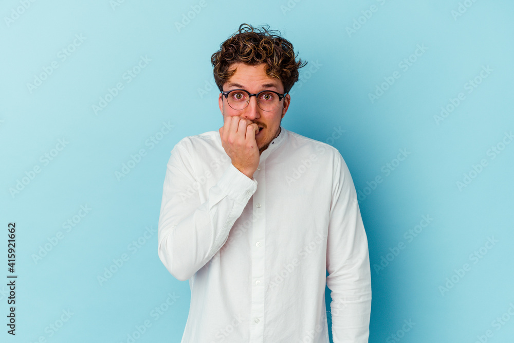Young caucasian business man isolated on blue background biting fingernails, nervous and very anxious. Young caucasian business man isolated on blue background biting fingernails, nervous and very anxious.