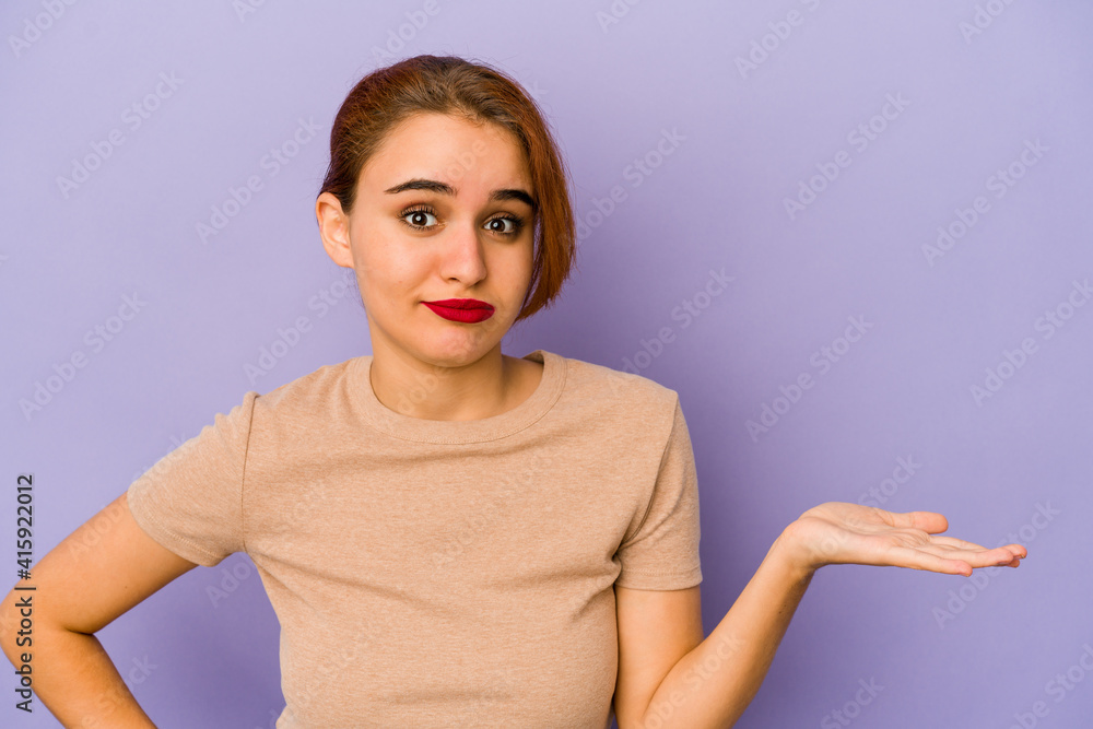 Young arab mixed race woman showing a copy space on a palm and holding another hand on waist. Young arab mixed race woman showing a copy space on a palm and holding another hand on waist.