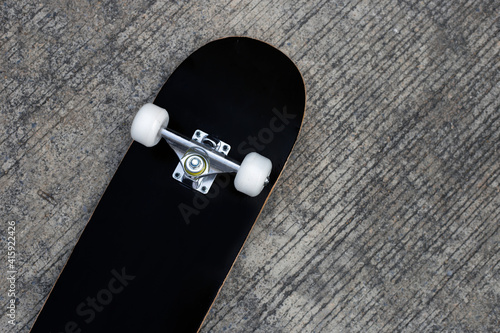 Black skateboard on cement ground.