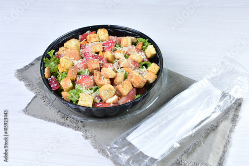 Rich very colorful vegetable salad, with croutons, strawberries, lettuce, Parmesan cheese and cherry tomato on white wooden background