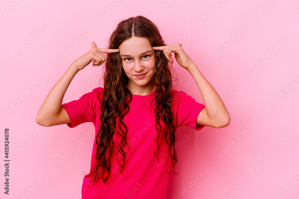 Little caucasian girl isolated on pink background focused on a task, keeping forefingers pointing head. Little caucasian girl isolated on pink background focused on a task, keeping forefingers pointing head.