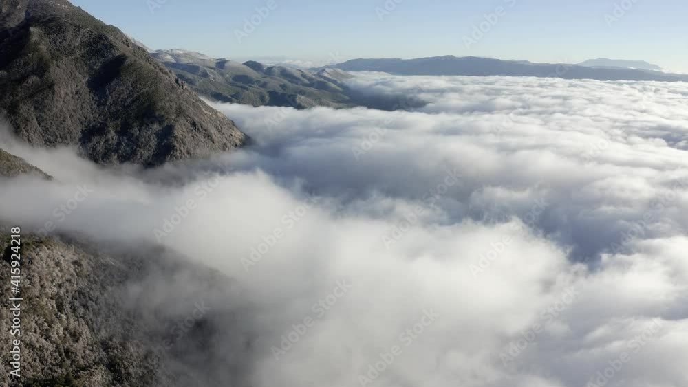 Mountain range peaks rising above lows clouds, high aerial view Mountain range peaks rising above lows clouds, high aerial view