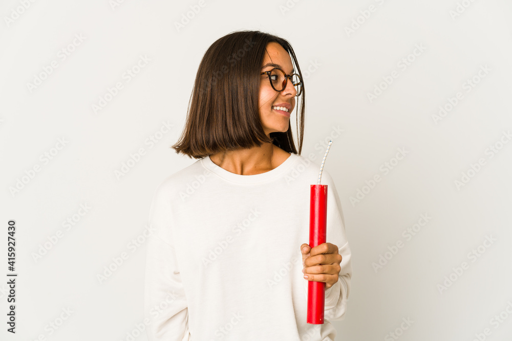 Young hispanic mixed race woman holding a dynamite looks aside smiling, cheerful and pleasant. Young hispanic mixed race woman holding a dynamite looks aside smiling, cheerful and pleasant.