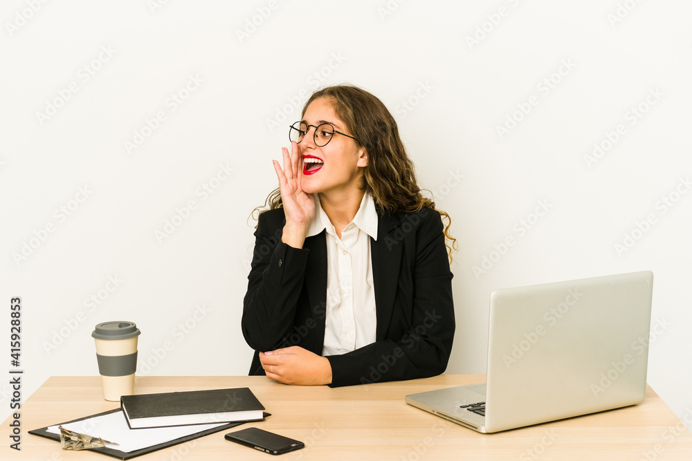 Young caucasian business woman working on her desktop isolated shouting and holding palm near opened mouth. Young caucasian business woman working on her desktop isolated shouting and holding palm near opened mouth.