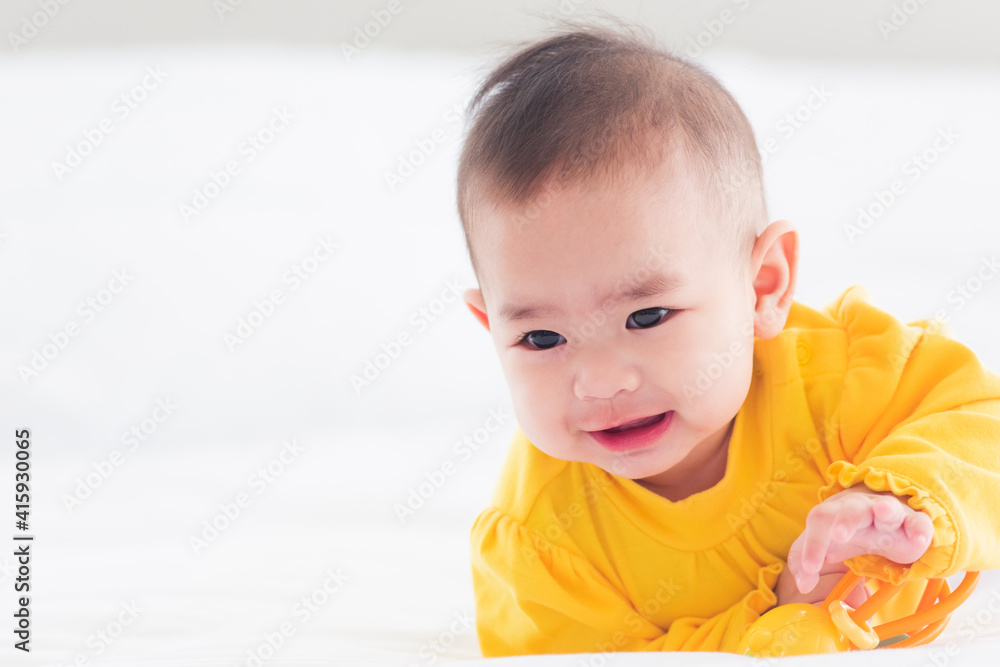 Portrait of beautiful young Asian newborn little baby prone on the bed at home, Happy baby smile wears a yellow shirt relaxing in the room, Family morning at home Portrait of beautiful young Asian newborn little baby prone on the bed at home, Happy baby smile wears a yellow shirt relaxing in the room, Family morning at home