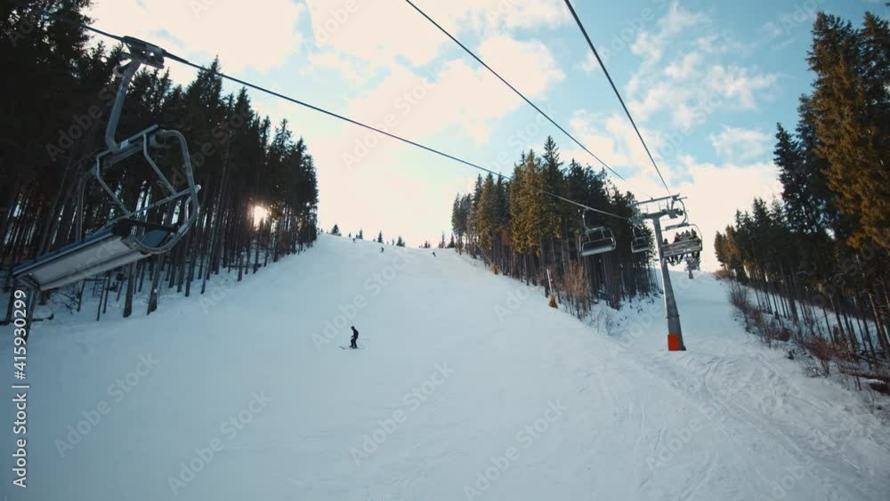 Winter ski resort. Skiers ride down snowy slopes on forest mountain. Large ski elevator lifting excited tourists on mountain top. Beautiful landscape. Activities concept.