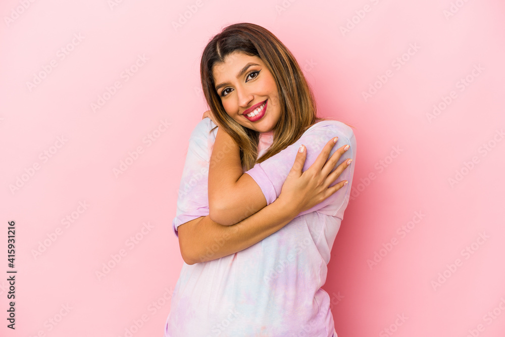 Young indian woman isolated on pink background hugs, smiling carefree and happy. Young indian woman isolated on pink background hugs, smiling carefree and happy.