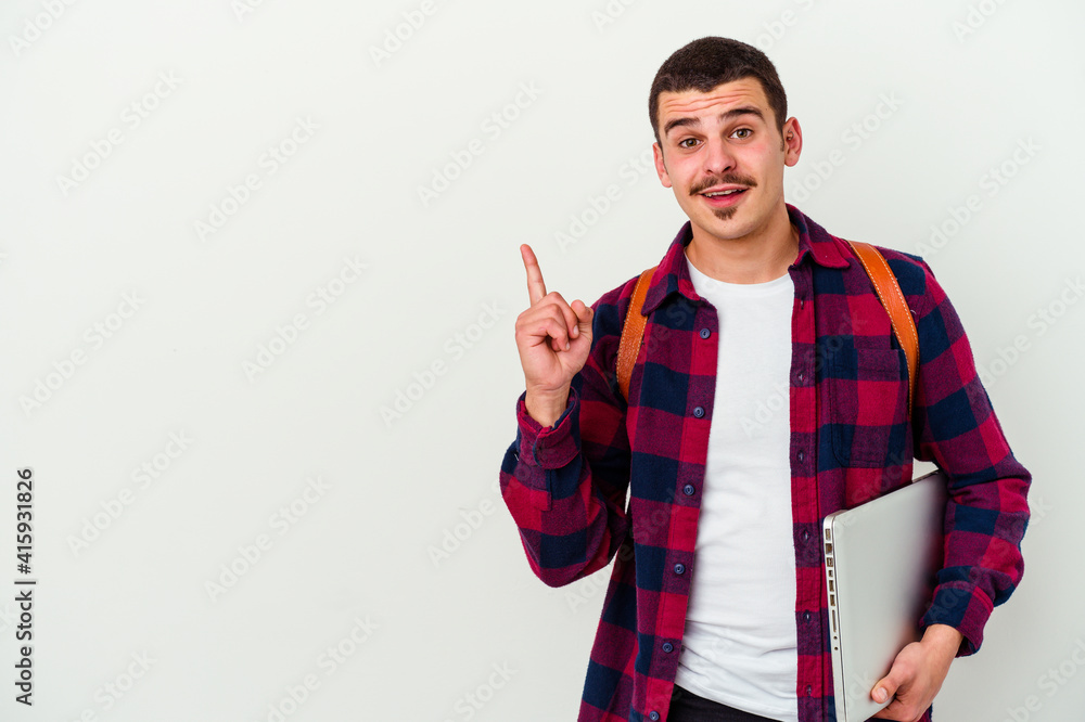 Young caucasian student man holding a laptop isolated on white background smiling cheerfully pointing with forefinger away. Young caucasian student man holding a laptop isolated on white background smiling cheerfully pointing with forefinger away.