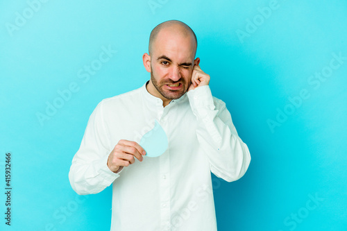Young caucasian bald man celebrating world water day isolated on blue background covering ears with hands. © Asier