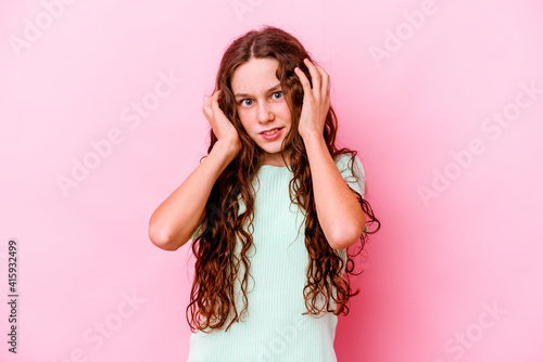 Little caucasian girl isolated on pink background covering ears with fingers, stressed and desperate by a loudly ambient. © Asier