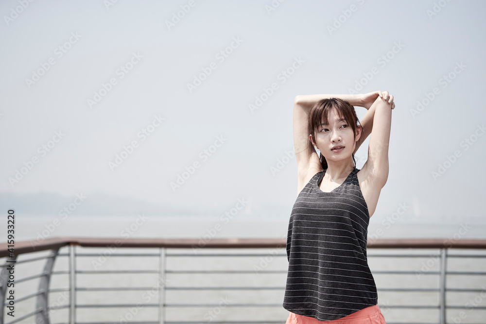 young asian woman stretching arms outdoors