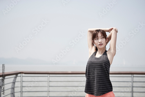 young asian woman stretching arms outdoors