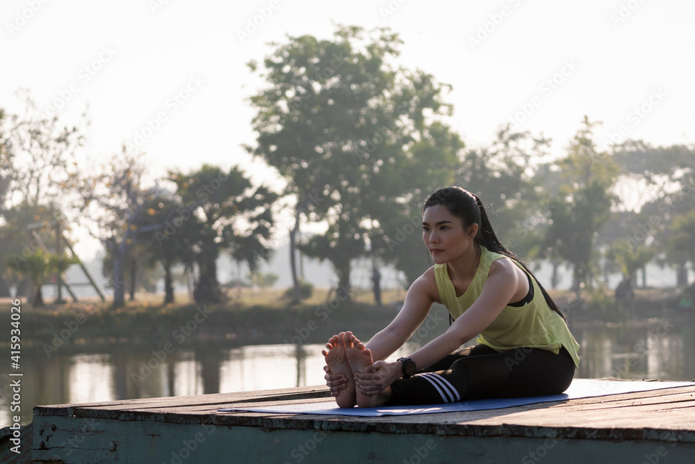 Young beautiful Asian woman in sports outfits doing yoga outdoor in the park in the morning with warm sunlight for a healthy lifestyle. Young woman yogi doing yoga in morning park Young beautiful Asian woman in sports outfits doing yoga outdoor in the park in the morning with warm sunlight for a healthy lifestyle. Young woman yogi doing yoga in morning park