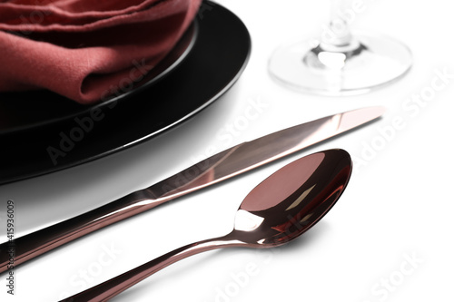 Elegant shiny cutlery near plates on white background  closeup