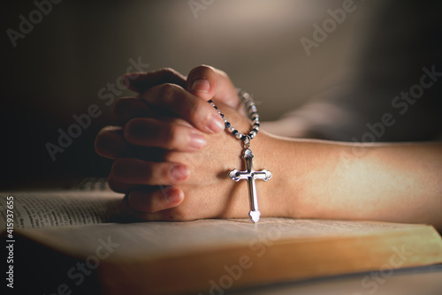 hands of religious christian woman holding jusus cross rosary praying to god