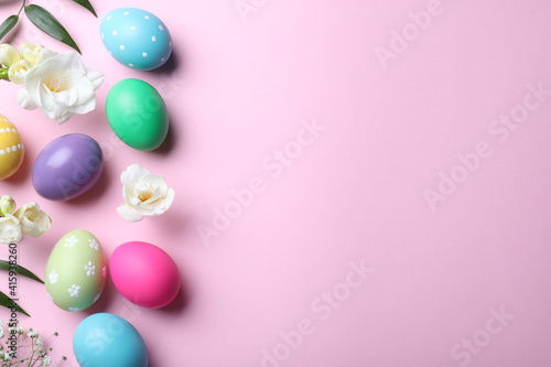 Bright painted eggs and flowers on pink background, flat lay with space for text. Happy Easter