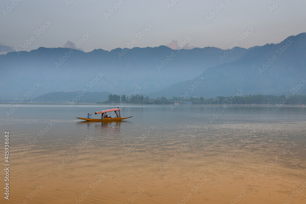 Reflection of Himalayan mountains on Dal Lake, Srinagar, Jammu and Kashmir, India. Houseboats floating on the lake in late afternoon.