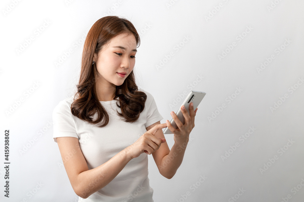 A young beautiful Asian woman looking and talking on a cell phone, she is texting, chatting, or social media videos with friends. An Online technology, online shopping concept. Over white background A young beautiful Asian woman looking and talking on a cell phone, she is texting, chatting, or social media videos with friends. An Online technology, online shopping concept. Over white background
