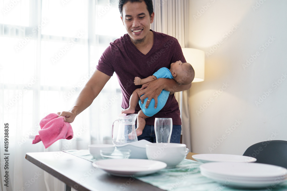 portrait of single father doing chores at home while carrying his baby portrait of single father doing chores at home while carrying his baby