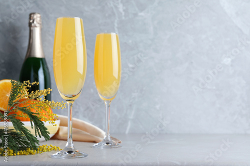Obraz na plátně Glasses of Mimosa cocktail on light table. Space for text