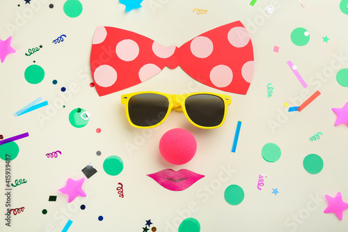 Flat lay composition with clown's face made of sunglasses and bow on white background