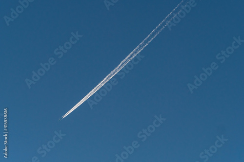 a jet flew over the clear blue sky left a long silver trail