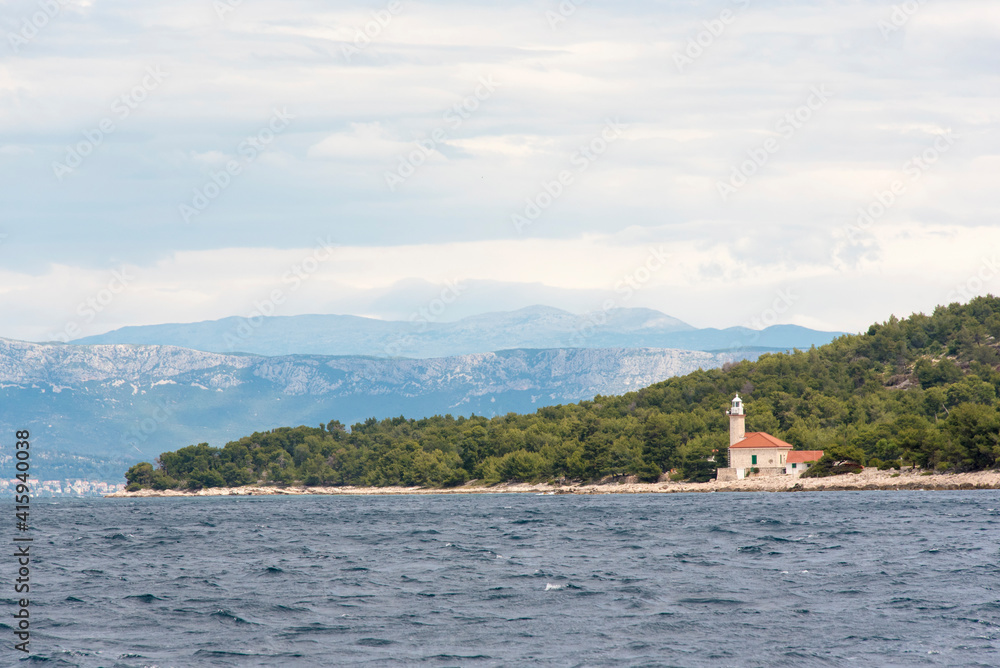 Croatia. Lighthouse Brac Island, mainland and Dinaric Alps behind.