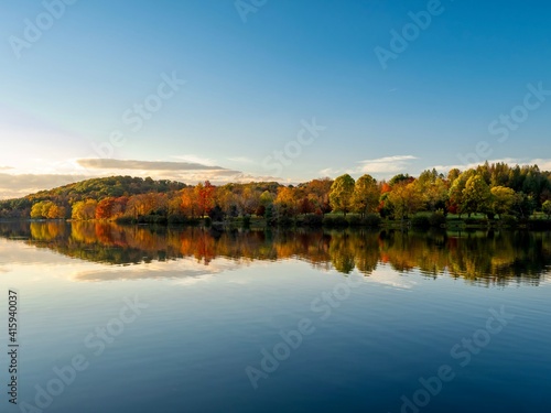 Keystone Lake in Keystone State Park in West Moreland County in the Laurel Highlands of Pennsylvania in the fall right before sunset with the fall foliage and trees reflecting in the water.