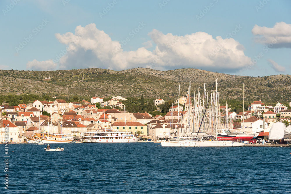 Croatia, Brac Island, Milna. Fisherman dwarfed by sailboats in Milna marina.