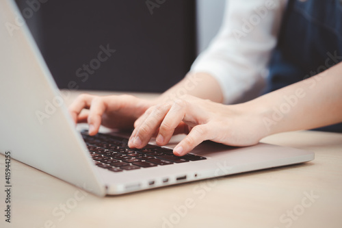 Unrecognizable Asian young woman using laptop computer.