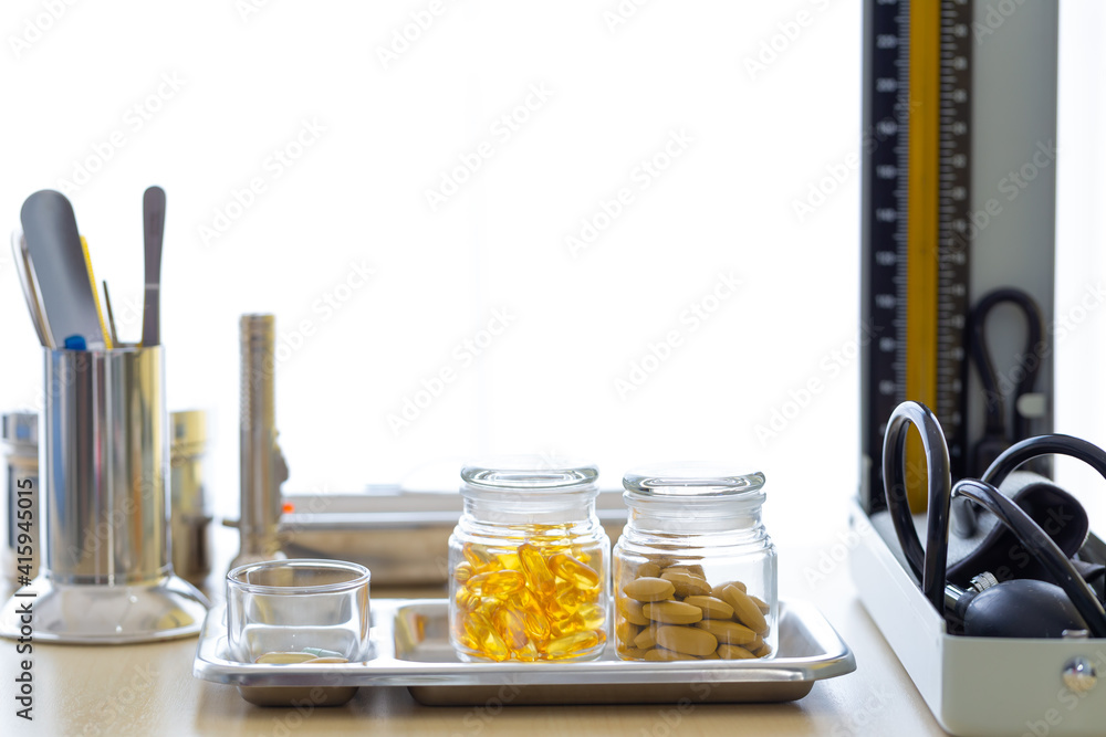 The bottle of vitamins is placed on the table with the doctor's equipment. The bottle of vitamins is placed on the table with the doctor's equipment.