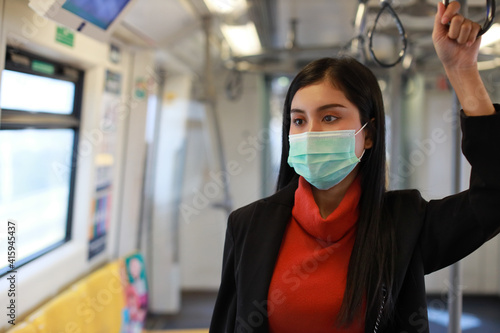 New normal covid-19 epidemic, young smart business asian woman wearing mask protection for prevent virus covid-19 or coronavirus infection from people in train or bad air pollution PM2.5 dusk