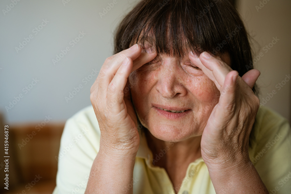 Portrait of a mature woman holding her head with her hands for headache at home, close-up Portrait of a mature woman holding her head with her hands for headache at home, close-up