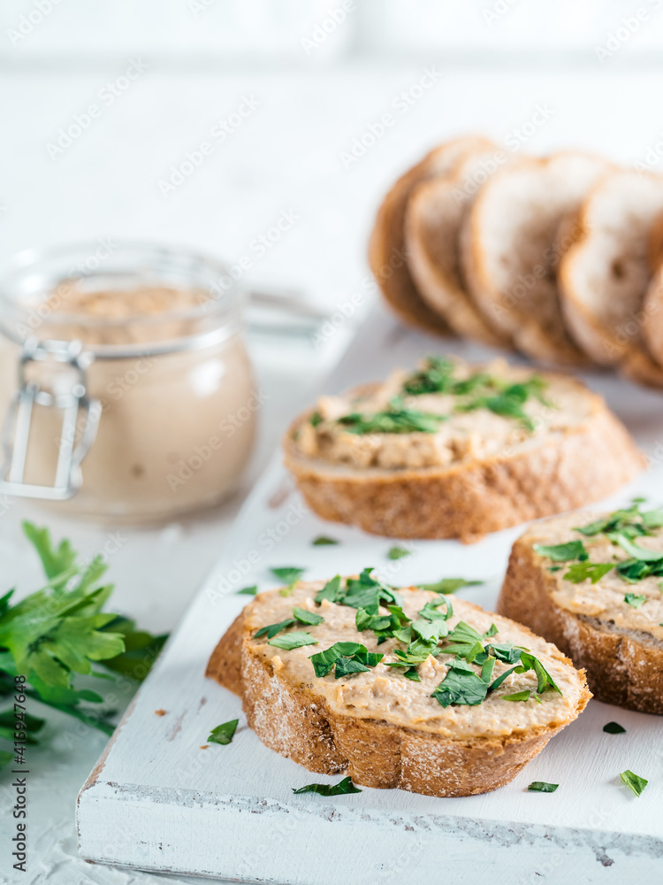Close up view of slice bread with homemade turkey pate and fresh green parsley on white rustic kutting board over white concrete background, Shallow DOF. Selective focus Close up view of slice bread with homemade turkey pate and fresh green parsley on white rustic kutting board over white concrete background, Shallow DOF. Selective focus