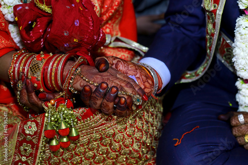 Groom holding bride hand with bangles and mehndi in Indian wedding photography with selective focus