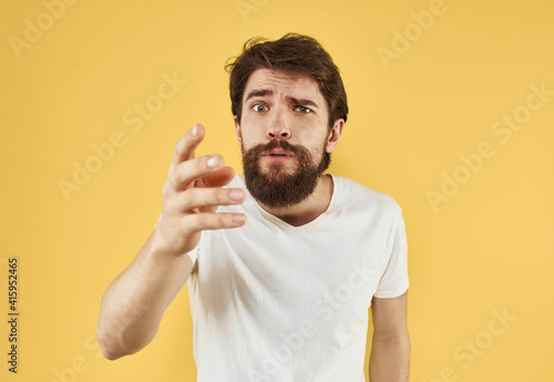 Portrait of a guy in a t-shirt and a brunet beard model yellow background