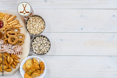 Beer with silhouettes of hockey stickson beer foam and snacks on light wooden background. Empty space for text. Top view photo