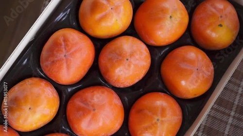 Bright orange persimmon folded in a box. Rotating camera, top view