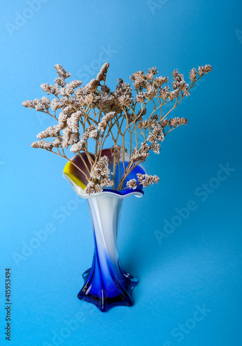 Goniolimon dried flower in a blue and white glass vase on a blue background