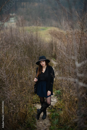 Woman in hat standing on narrow path among shrubs © WellStock
