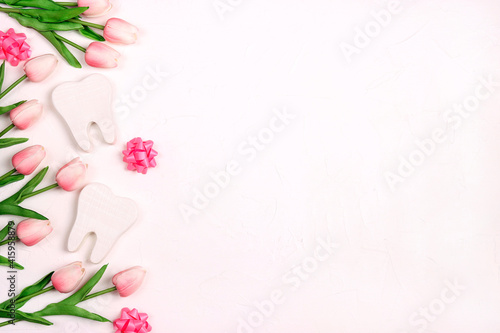 Festive dental background with teeth, bows and pink tulips on a white background with copy space for text.