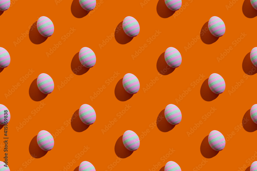 Easter seamless pattern. Festive banner. Holiday decoration. Abstract background. Colorful eggs of pink and green striped ornament isolated on orange.