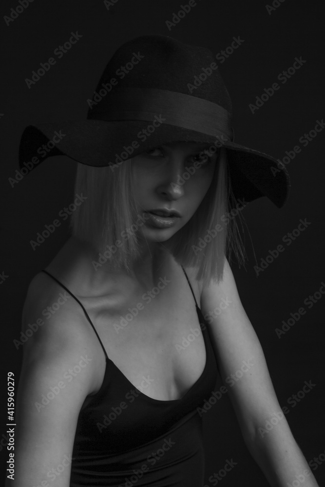 Black and white portrait blondes on a black background in a hat and Tank Top With Thin Straps. Black and white portrait blondes on a black background in a hat and Tank Top With Thin Straps.