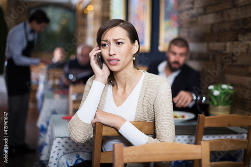 sad adult visitor female in restaurant talking mobile phone © JackF