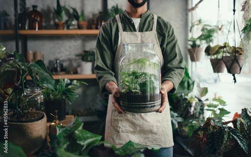 Shop assistant holding terrarium in indoor potted plant store, small business concept. photo